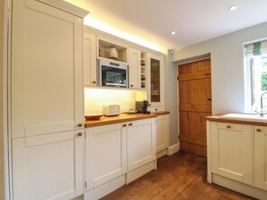 A kitchen with white cabinetry, a microwave, and a toaster. - The Chimes (Hope Valley)