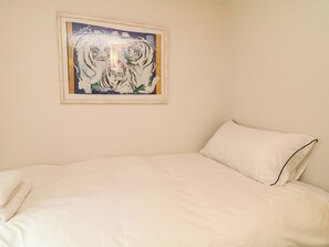 Een slaapkamer met een bed, een lijst met tijgers en een effen muur.
