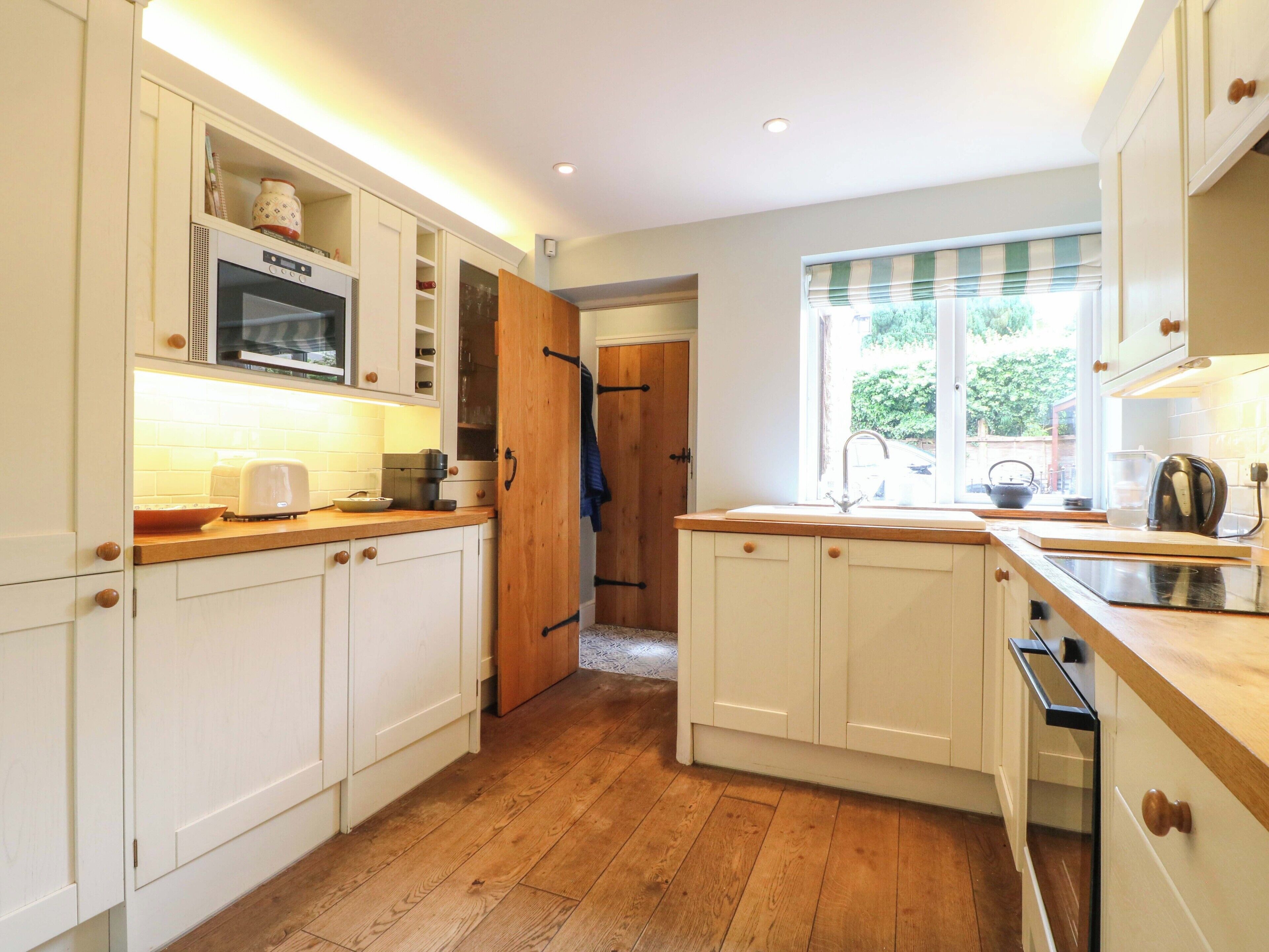 A kitchen with white cabinets, a microwave, and a window with blinds.