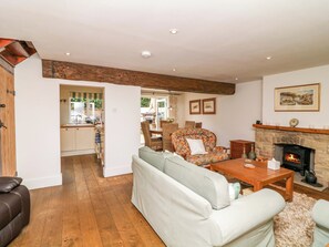 A cozy living room with a sofa, a wooden coffee table, and a fireplace. - The Chimes (Hope Valley)
