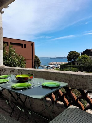 A table set with green plates and glasses, overlooking a marina with boats and a distant view of the sea. - Family home on the port of Le Niel (Hyères)