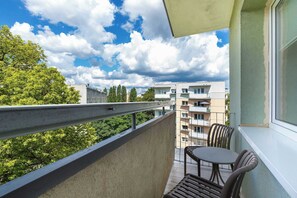 Een balkon met een tafel en stoelen, uitzicht op gebouwen en een heldere lucht.