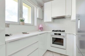 Moderni keittiö, jossa on valkoiset kaapit, sisäänrakennettu uuni ja ikkuna, josta on kaunis näkymä.
