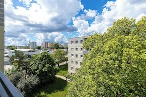 A residential area with multi-story buildings, trees, and a clear sky.
