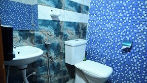 Et badeværelse med en hvid vask, toilet og brusebad.