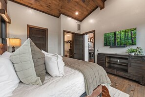 Ein Schlafzimmer mit einem Bett, einer Kommode, einem Spiegel und Wandbildern mit Waldmotiv.