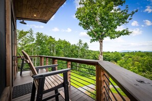 Eine Holzterrasse mit Geländer, einer Bank und einer Tür zu einem überdachten Bereich.
