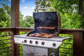 Ein Grill mit mehreren Kochzonen, einem Metallgriff und einer Bedienblende mit Drehreglern.