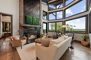 Ein geräumiges Wohnzimmer mit Kamin, großen Fenstern und Blick ins Freie.