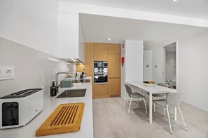 Eine moderne Küche mit Backofen, Spüle und Essbereich inklusive Tisch und Stühlen.