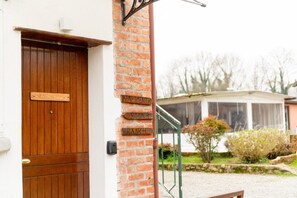 Een houten deur met een bord waarop 'Appartement' en 'Kamer 3' staat, tegen een bakstenen muur.