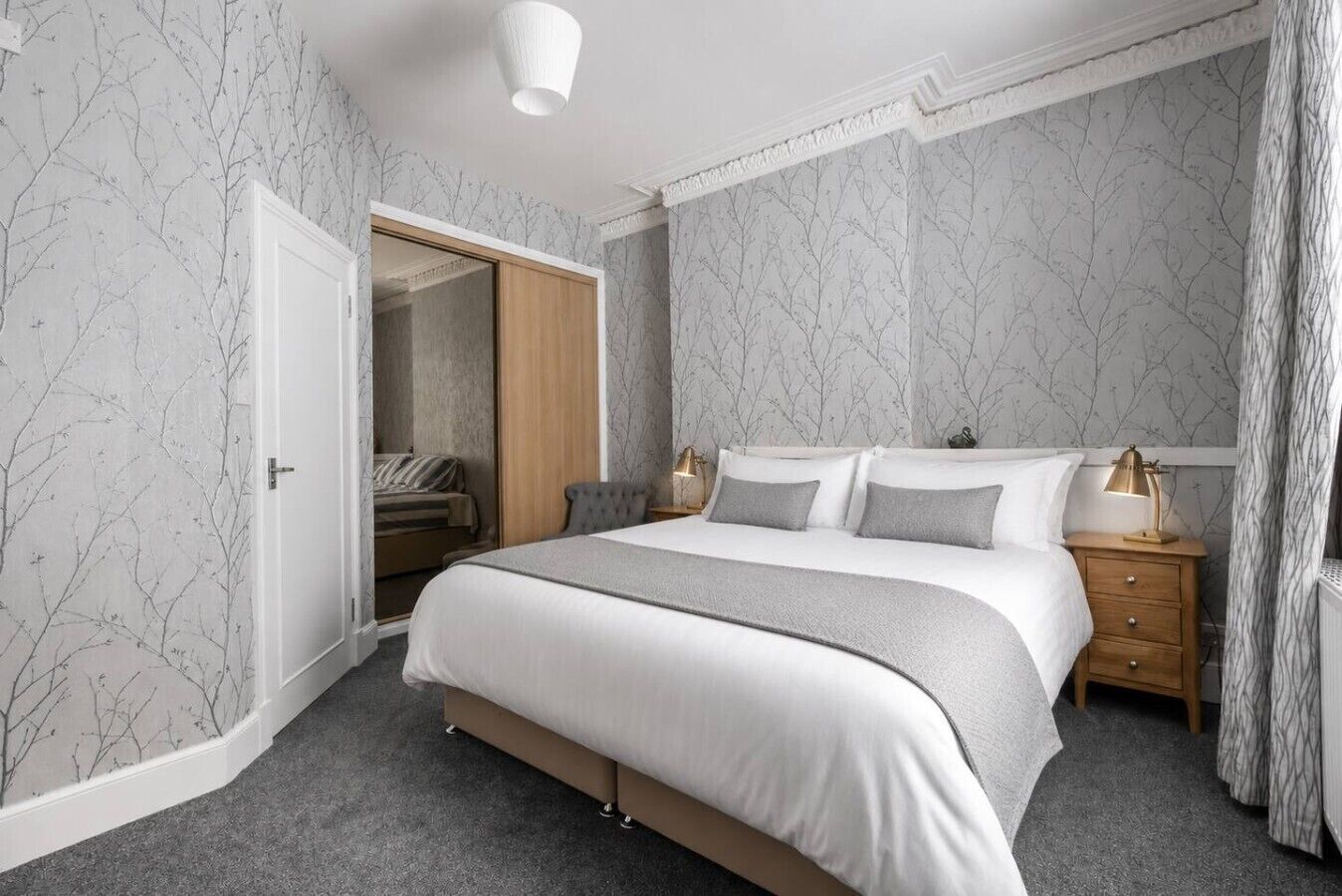 A bedroom with a bed, bedside tables, a nightstand, a lamp, and a wardrobe.