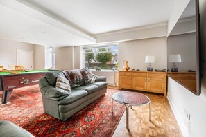 A living room with a sofa, a pool table, a small round table, and a cabinet. - Coldside House - Well Connected Dundee Stay (Dundee)