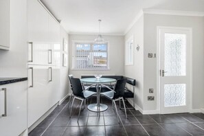 A modern kitchen with white cabinets, a round dining table, and black chairs. - Coldside House - Well Connected Dundee Stay (Dundee)