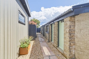 A narrow pathway leading to a building with a stone facade and a metal exterior. - 20 Applegrove - Home from Home in Monifieth (Monifieth)