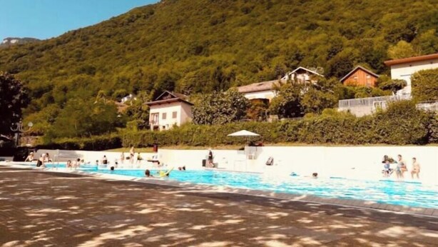 A swimming pool area with people, surrounded by houses and a hill. - Furnished apartment, 76 m², 30 m² terrace, view of Belledonne (Saint-Vincent-de-Mercuze)