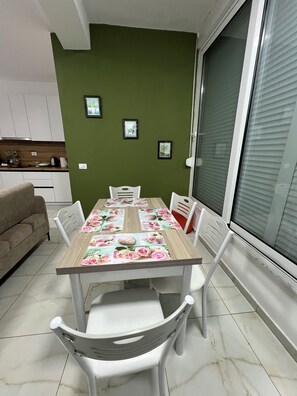 En matplats med ett bord dukat för fyra personer, omgiven av vita stolar, en grön vägg och inramade tavlor.