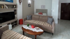 Ein Wohnzimmer mit einer Couch, einem Couchtisch, einem Fernseher und einem Gemälde an der Wand.