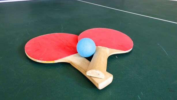 Ein Tischtennis-Tisch mit Ball und Schlägern.