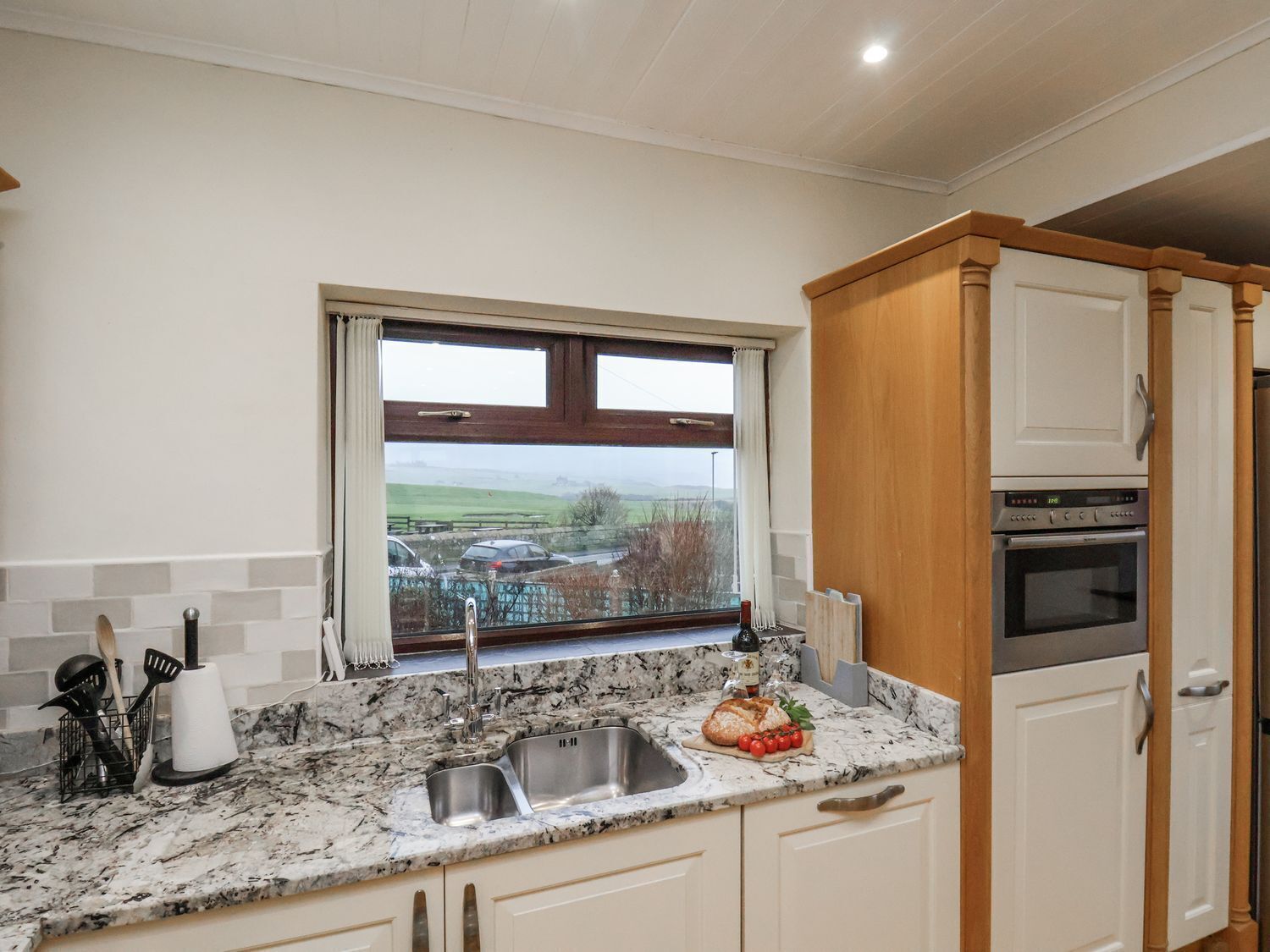 Una cocina con un lavamanos, encimera, armarios y una ventana con vistas al exterior.