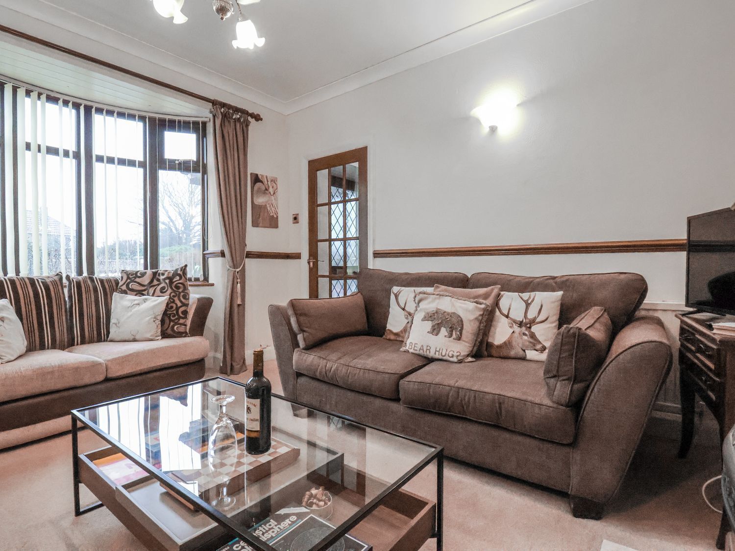 A living room with a sofa, a glass coffee table, and a television.
