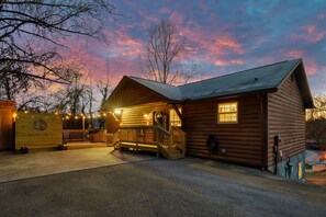 Eine Blockhütte mit Veranda, einem Willkommensschild und einer kleinen Holzterrasse.