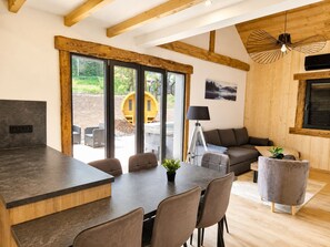 A modern interior with a kitchen, dining area, and a sofa set. - "LSN6" Chalet: Cozy & High-End Comfort with Sauna, Spa, Air Conditioning, Foosball, and Pool (Anould)