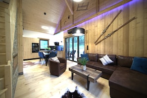 A wooden interior with a sofa, coffee table, and a dining area. - Cozy, high-end chalet with sauna, spa, air conditioning, foosball, and a pool (Anould)