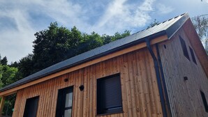 Una cabaña de madera con techo metálico, una puerta y dos ventanas.