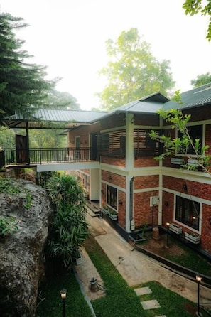A two-story building with a brick facade, a covered patio, and a small garden area.