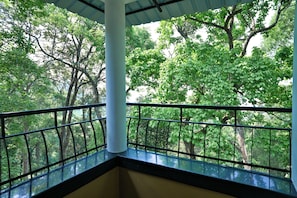 A balcony with a metal railing overlooking a forested area.