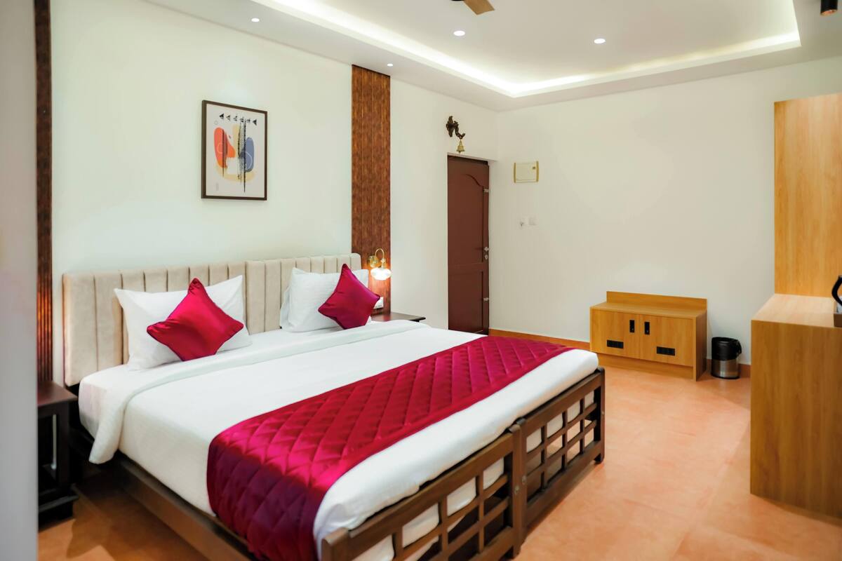 A hotel room with a bed, a wooden cabinet, a door, and a wall-mounted artwork.
