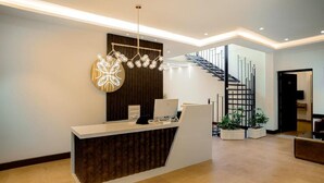 A reception desk with a modern design, a staircase, and potted plants. - Aroma Hills Resort (Udumbanchola)