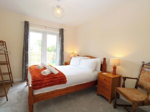 Een slaapkamer met een houten bed, twee nachtkastjes, een stoel en een raam met gordijnen.