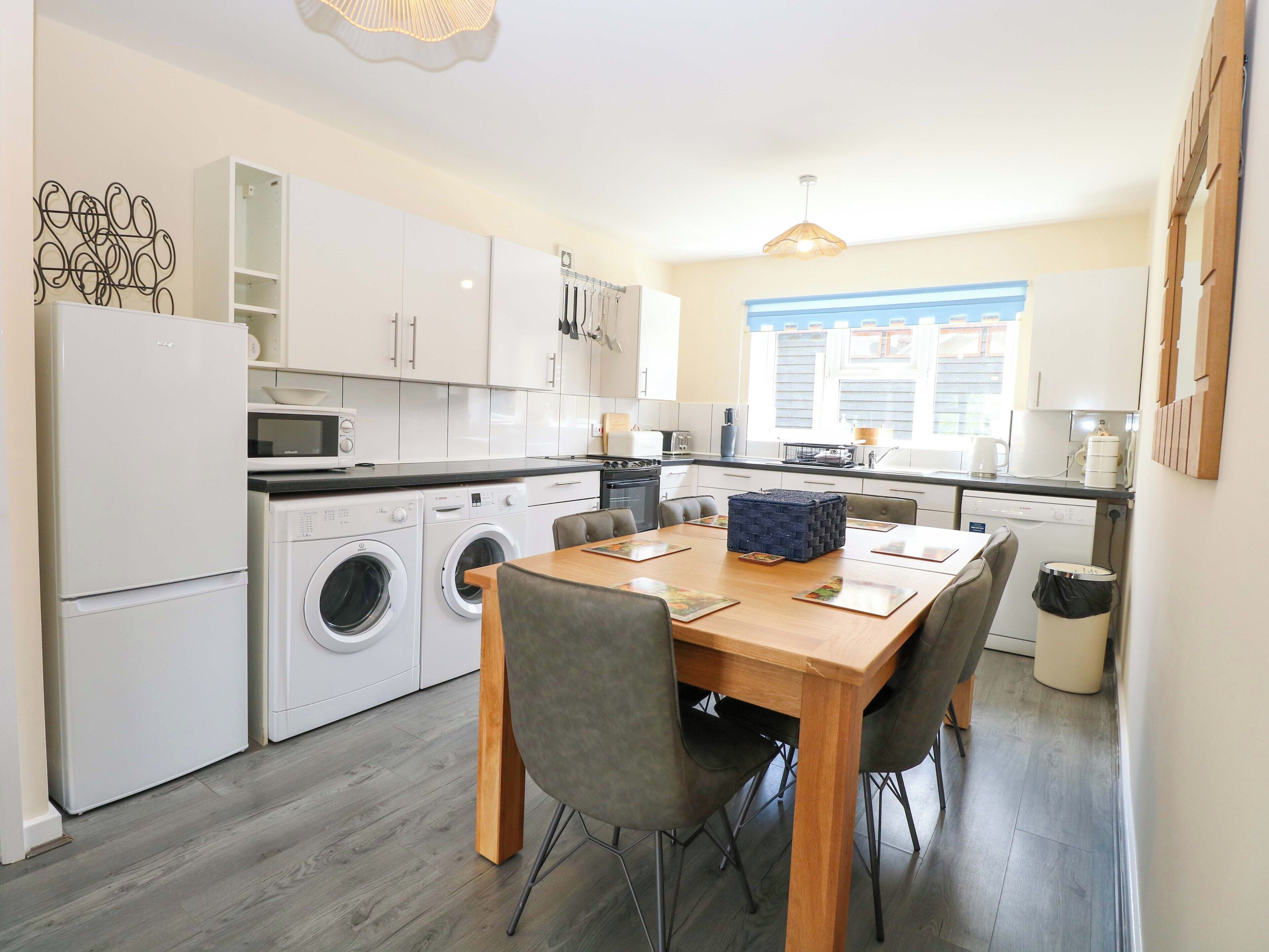 A compact kitchen with a dining area, including a washing machine, microwave, and a table with chairs.