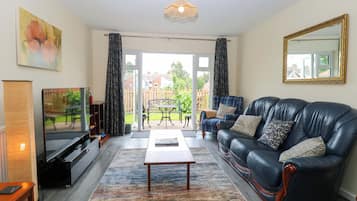 A living room with a sofa, television, and a view of the outside.