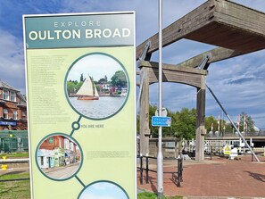 Un cartel con información sobre Oulton Broad, incluyendo una foto de un velero en el agua.
