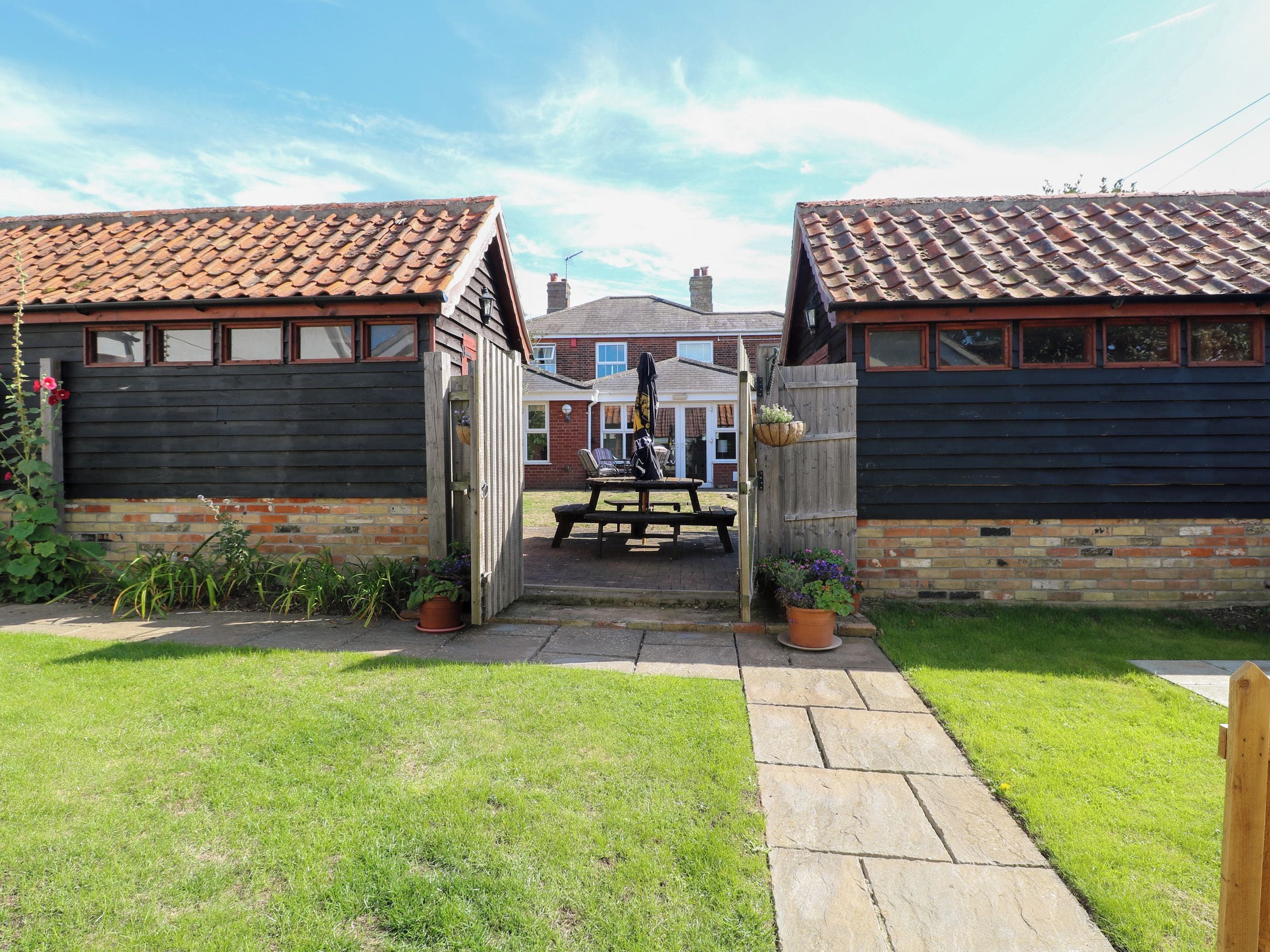 A wooden gate leading to a patio area with a picnic table and potted plants.