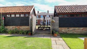 A wooden gate leading to a patio area with a picnic table and potted plants.