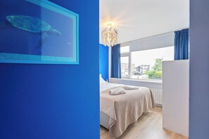 A room with a bed, a window with curtains, a wall with a framed picture, and a ceiling light fixture. - Family House Fahrenheit - dunes, garden and room for six (Zandvoort)
