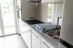 A modern kitchen with a stainless steel sink, a built-in oven, and a window overlooking a green area. - Villa Livi · Quiet 1BR for 4 · AC · Free Parking · Medulin (Medulin)