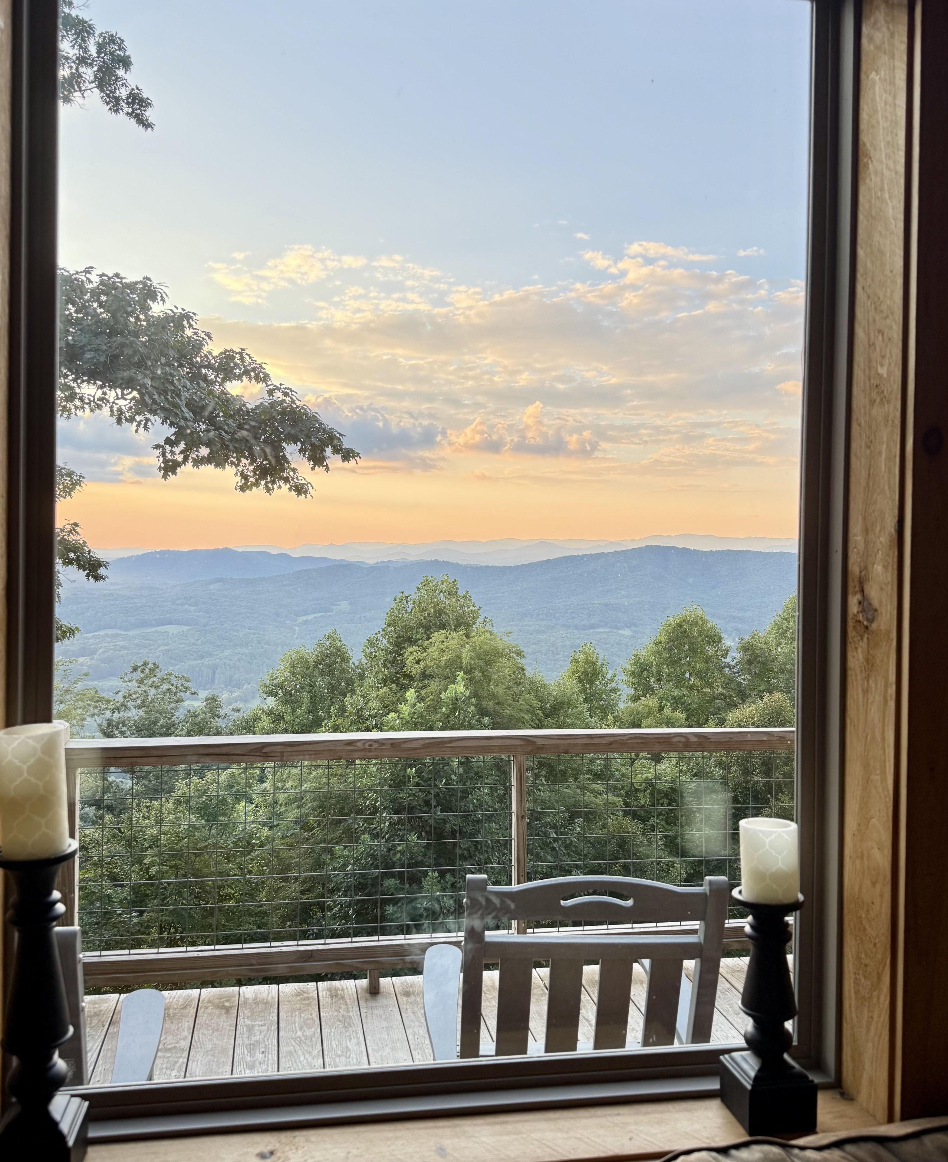 A wooden deck with a bench and two candle holders, overlooking a mountainous landscape.