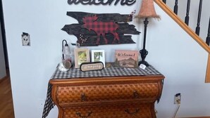 Una scala con un cartello che dice 'welcome', una parete in legno rustica e un tavolo con una tovaglia a quadri.