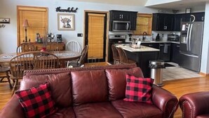 Un soggiorno con un divano in pelle marrone, un tavolo da pranzo e una zona cucina con elettrodomestici moderni.