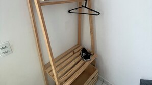 Een hoekkamer met een houten wandplank, een kledingstuk aan een kapstok en een stopcontact.