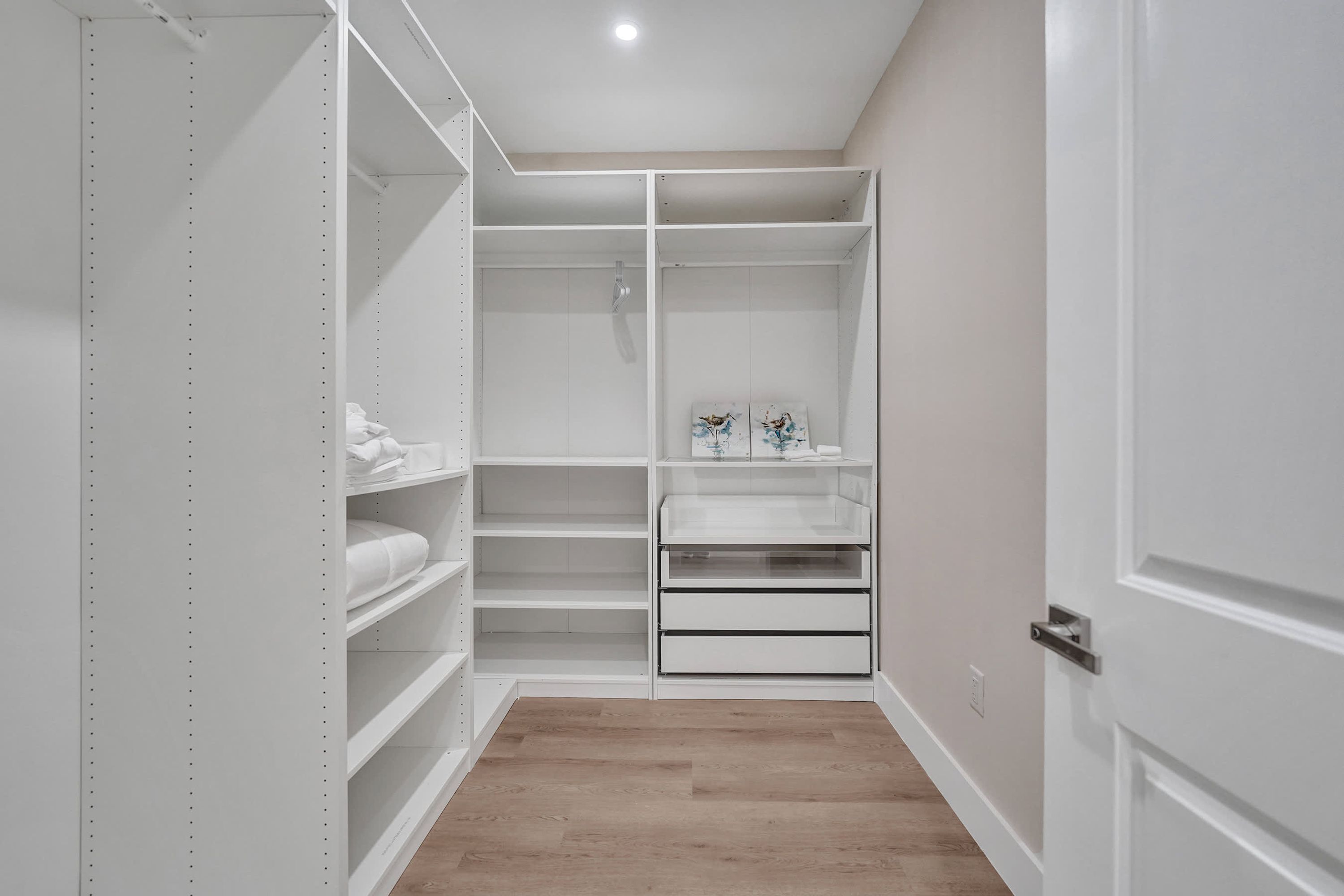 A walk-in closet with open shelving, a hanging rod, and a small vanity area.