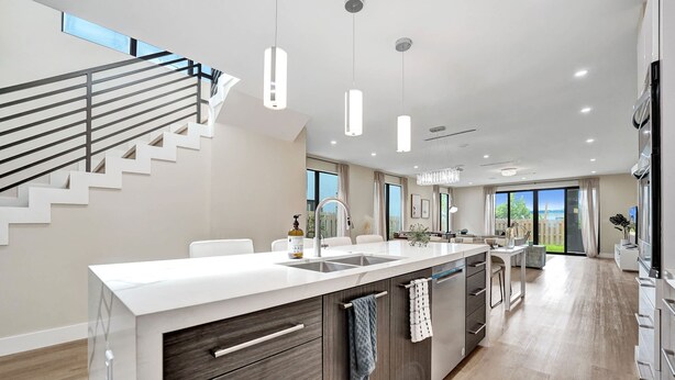Una cocina moderna con una isla central, electrodomésticos integrados y una escalera con barandilla.
