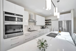 Uma cozinha moderna com eletrodomésticos embutidos, uma ilha central e iluminação pendente.