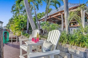 A wooden deck with Adirondack chairs, a small table, and a green garden hose. - Waterfront With Pool Spa Tiki Bar and 1 Mile to Beach (Fort Lauderdale)