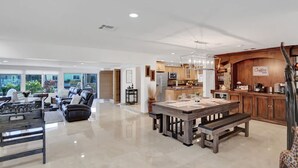 A spacious living area with a dining table, a sofa, and a kitchen area with a coffee bar. - Waterfront With Pool Spa Tiki Bar and 1 Mile to Beach (Fort Lauderdale)